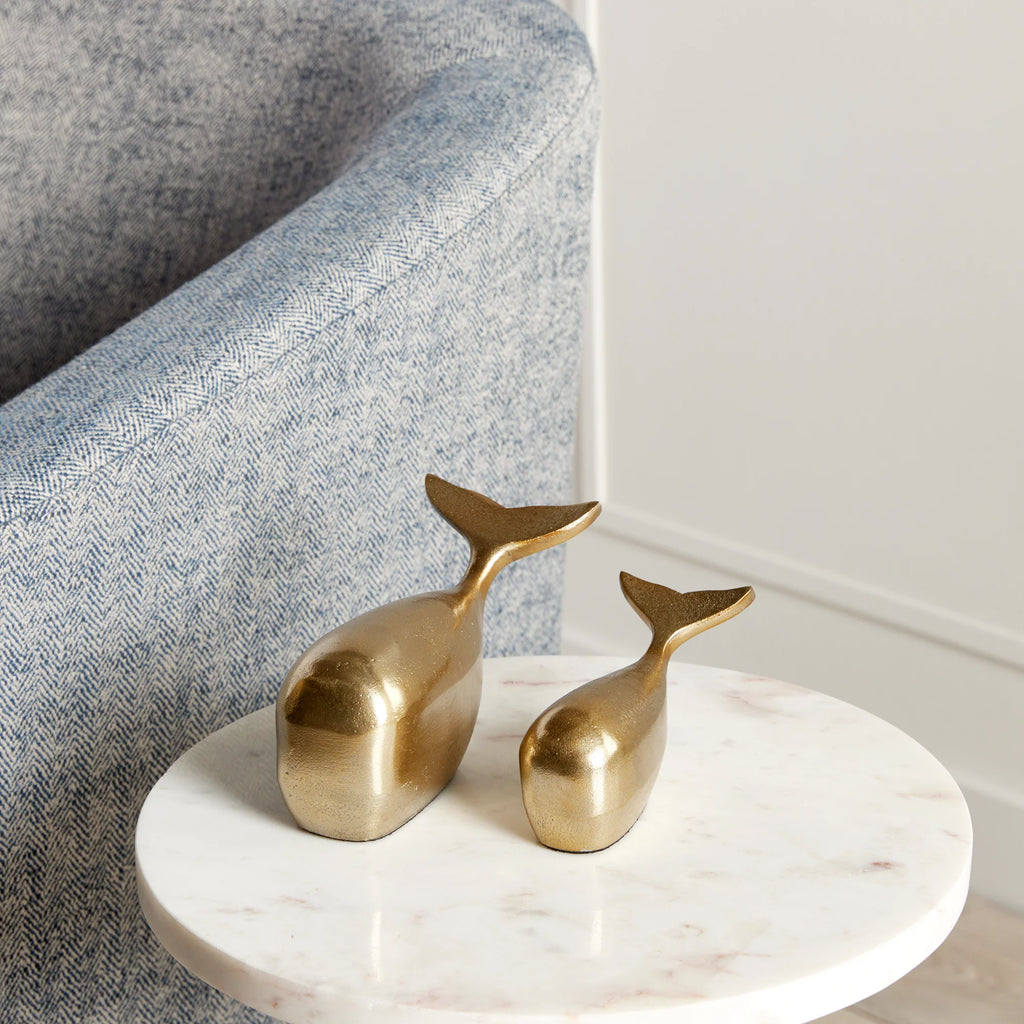 Set of two Moby Whale Sculptures in the color gold on a table.